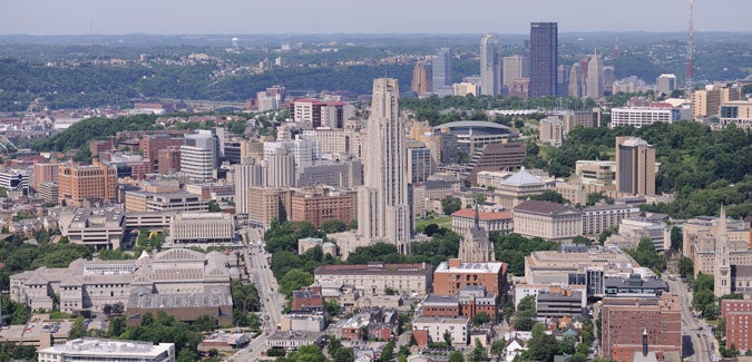 An aerial view of Oakland with the downtown Pittsburgh skyline in the background